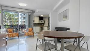 A modern apartment with a dining area, kitchen, and balcony. - Apartment with pool and parking 350m beach (Cambrils)