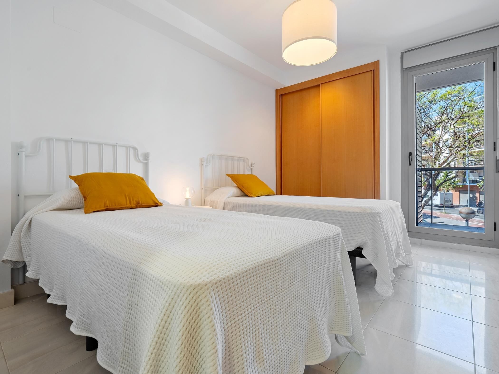 Habitación de hotel con dos camas, un armario de madera y un ventanal con vistas al exterior.