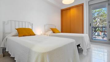 Habitación de hotel con dos camas, un armario de madera y un ventanal con vistas al exterior.