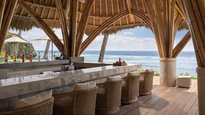 A beachside bar with a bamboo roof, wicker furniture, and a view of the ocean. - Semaya Beach Resort (Penida Island)