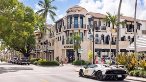 Un bâtiment avec une enseigne « CHASE », un panneau indiquant un parking, et une Lamborghini garée devant.