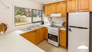 A compact kitchen with wooden cabinets, a gas stove, a microwave, and a refrigerator.