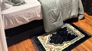 Un dormitorio con una cama, una alfombra y dos cuadros en la pared.