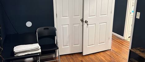 A bedroom with a bed, a desk with a chair, and a closet with two doors.