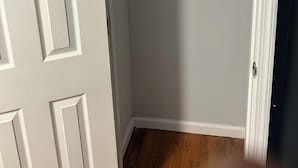 Un armario con puerta blanca, suelo de madera y barra para colgar blanca.