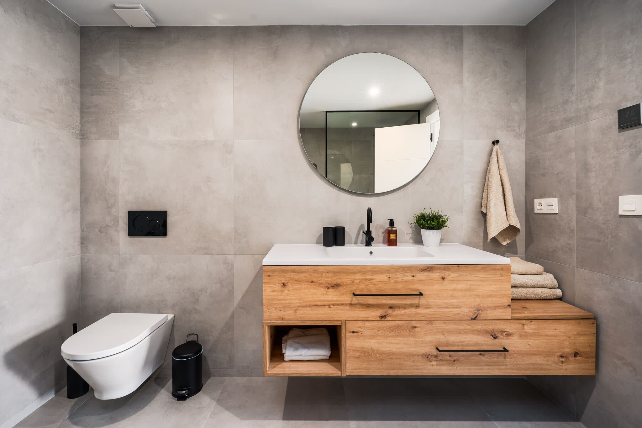 A modern bathroom with a toilet, a vanity with a mirror, and a towel rack.