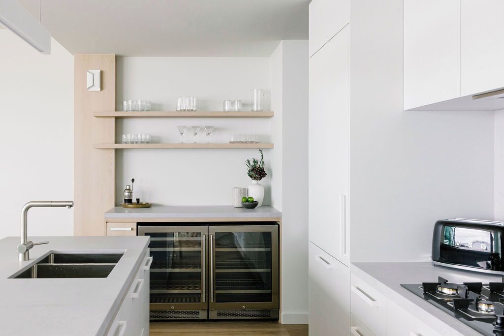 A modern kitchen with a built-in oven, a stainless steel sink, and a toaster on the countertop.