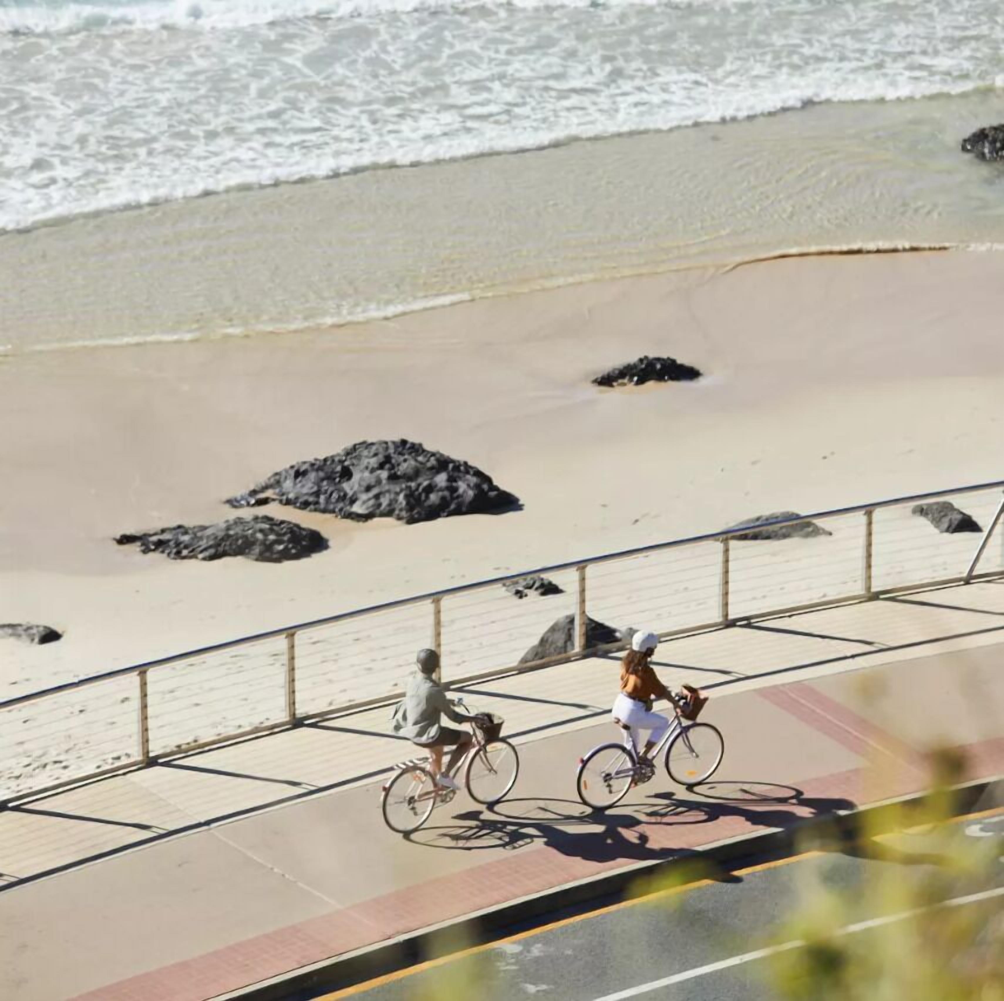 A beach with a paved walkway and a railing.