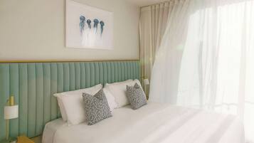 A hotel room with a bed, pillows, a nightstand, a lamp, and a framed picture on the wall.