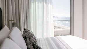A bedroom with a bed, white curtains, and a view of the beach. - Kirra Point Holiday Apartments (Coolangatta)