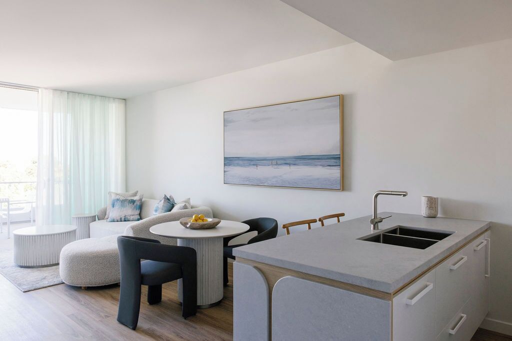 A modern kitchen with a built-in sink, a dining area with a round table, and a sofa.