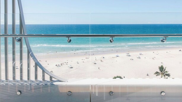 A beach view from a balcony with a railing, clear sky, and ocean. - Kirra Point Holiday Apartments (Coolangatta)