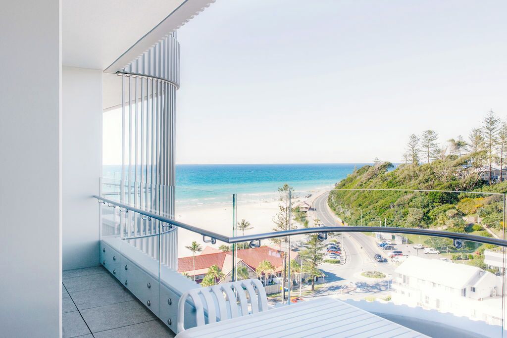 A balcony with a view of a beach and a road.