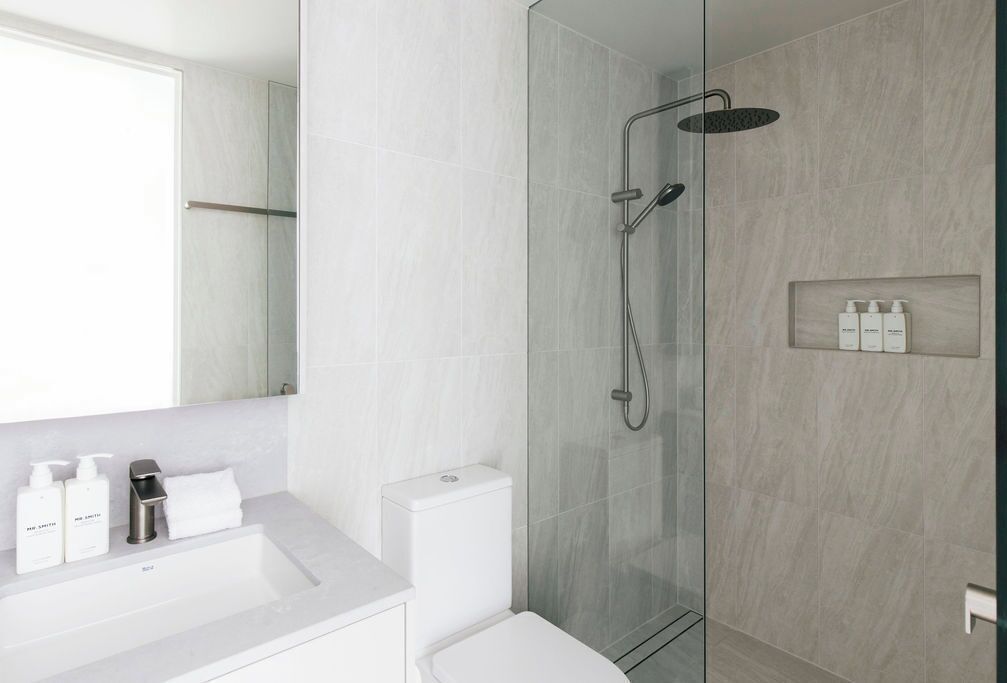 A modern bathroom with a glass-enclosed shower, a white sink, and a mirror.