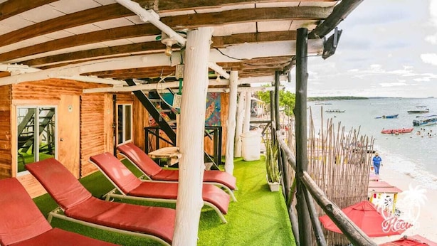 Een strandlounge met rode ligbedden en uitzicht op zee.