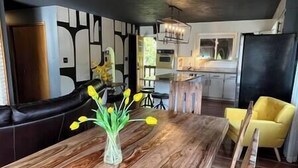 A modern kitchen with a wooden dining table, yellow chairs, and a vase of flowers. - Vibrant Forest Retreat | Game Room, Spa, Fire Pit - Sleeps10 (Spirit Lake)