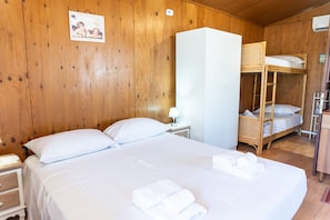 Una habitación de madera con una cama, un armario y una litera.