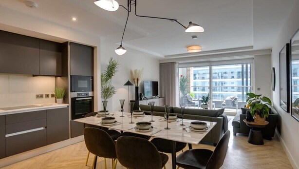 A modern kitchen with a dining area, large windows, and a view of the city.