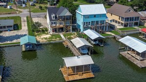A waterfront property with multiple houses, docks, and a small boat. - It's About River Time, a 3BR/3BA house on False River, fenced yard & large pier! (Jarreau)
