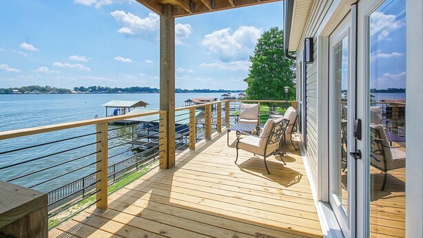 A wooden deck with outdoor furniture overlooking a lake. - It's About River Time, a 3BR/3BA house on False River, fenced yard & large pier! (Jarreau)