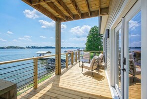 En træterrasse med udendørs møbler med udsigt over en sø.