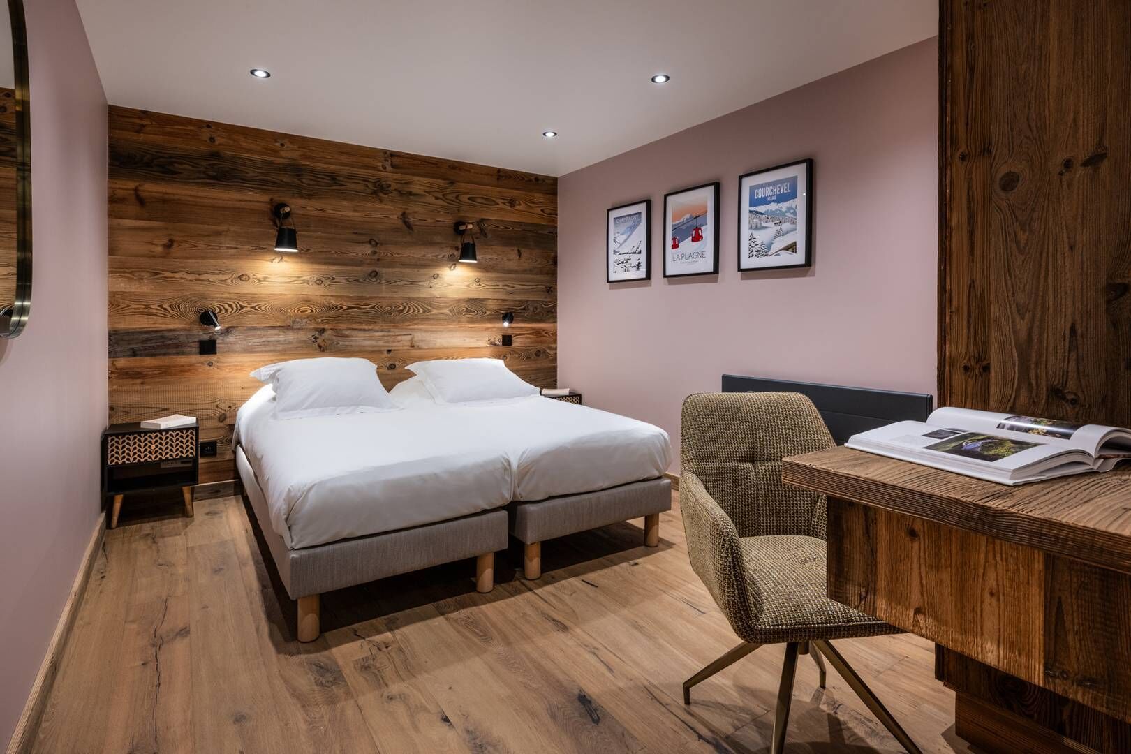 Ein modernes Schlafzimmer mit einem Holzkopfteil, einem Doppelbett, Nachttischen, einem Sessel und einem Schreibtisch mit einer Zeitschrift.
