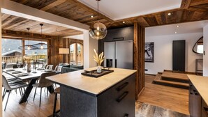 A modern kitchen with a central island, wooden ceiling, and large windows overlooking a mountainous area. - N°2: Beautiful 10 people apartment with sauna  et  south facing terraces (CHAMPAGNY EN VANOISE)