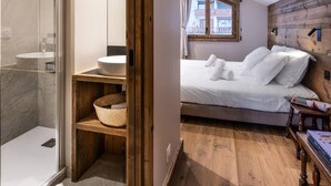 A bedroom with a wooden headboard, a bed with white linens, a bedside table, and a window with curtains.