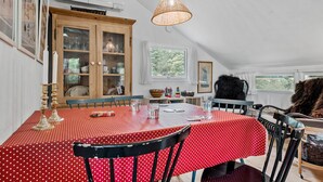 A dining area with a red polka dot tablecloth, wooden cabinets, and a hanging light fixture. - 2 bedroom nice home in Højby (Højby)