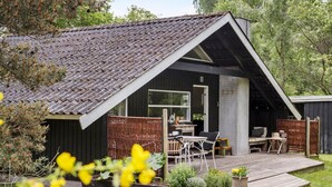A modern, black-roofed cabin with a wooden deck, outdoor seating, and a garden area. - 2 bedroom nice home in Højby (Højby)