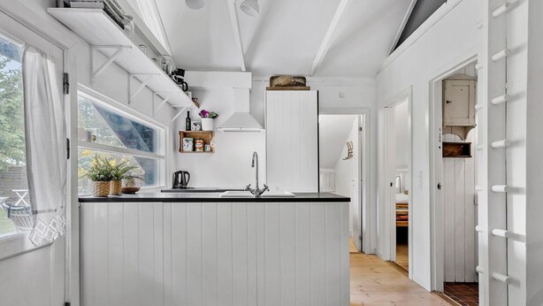 A kitchen with white cabinetry, a central island with a sink, and a window with a view of the outdoors. - 2 bedroom nice home in Højby (Højby)