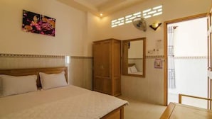 A bedroom with a bed, a wardrobe, a mirror, and a window. - My Tuoi Hotel Phu Quoc - by Bay Luxury (Phu Quoc)