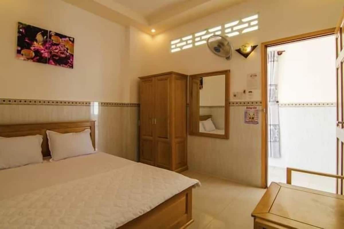 A bedroom with a bed, a wardrobe, a mirror, and a window.