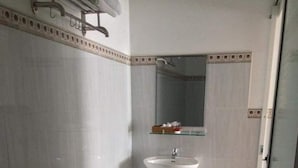 A small, clean bathroom with a toilet, sink, and mirror. - My Tuoi Hotel Phu Quoc - by Bay Luxury (Phu Quoc)
