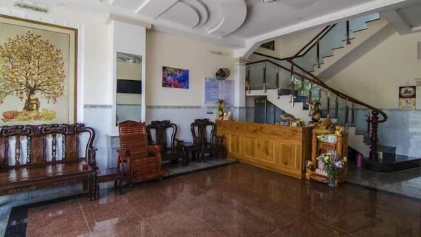 A lobby with a wooden bench, a reception desk, a staircase, and a painting of a tree. - My Tuoi Hotel Phu Quoc - by Bay Luxury (Phu Quoc)
