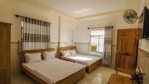 A hotel room with two wooden beds, a wooden wardrobe, a small wooden table, and a ceiling fan. - My Tuoi Hotel Phu Quoc - by Bay Luxury (Phu Quoc)