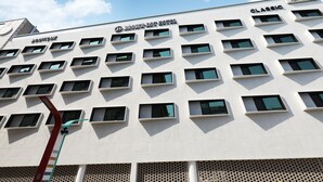 Un hôtel moderne, avec de nombreuses fenêtres et une enseigne indiquant « HÔTEL BROWN-DOT ».