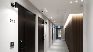 Un couloir d’hôtel moderne avec des portes en bois foncé numérotées 518, une moquette de couleur claire et des luminaires encastrés au plafond.