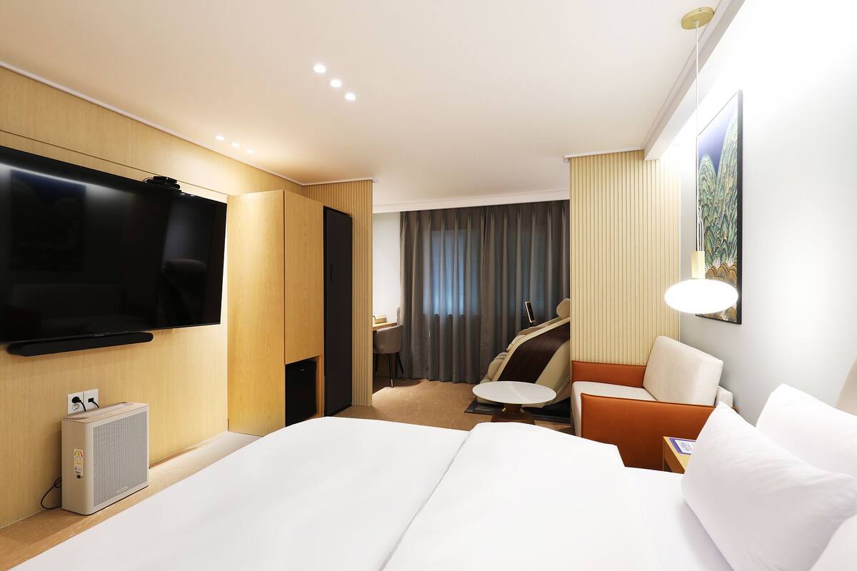 Une chambre d’hôtel avec un lit, une télévision, un bureau, une chaise et un tableau au mur.