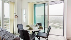 Ein Essbereich mit einem runden Tisch für vier Personen, Stühlen und Blick durch eine Glastür nach draußen.