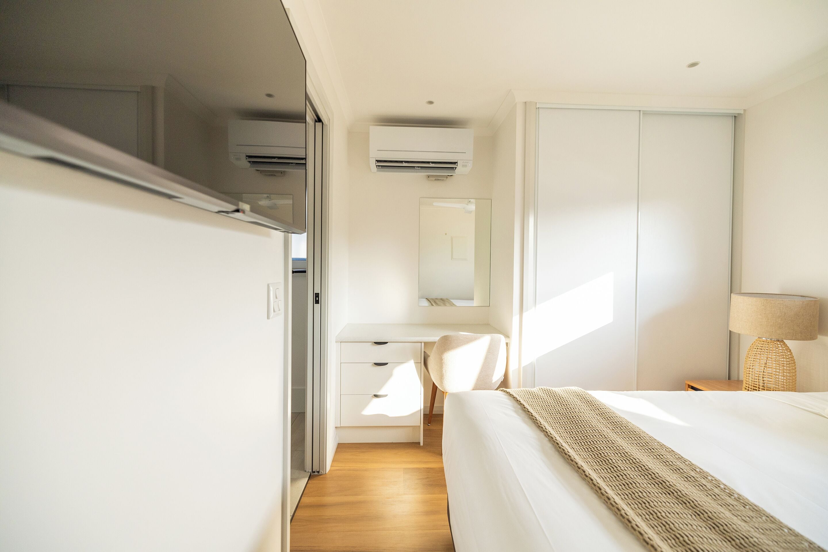 A modern bedroom with a bed, a desk, and a wardrobe.