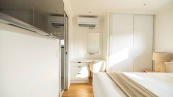 A modern bedroom with a bed, a desk, and a wardrobe.