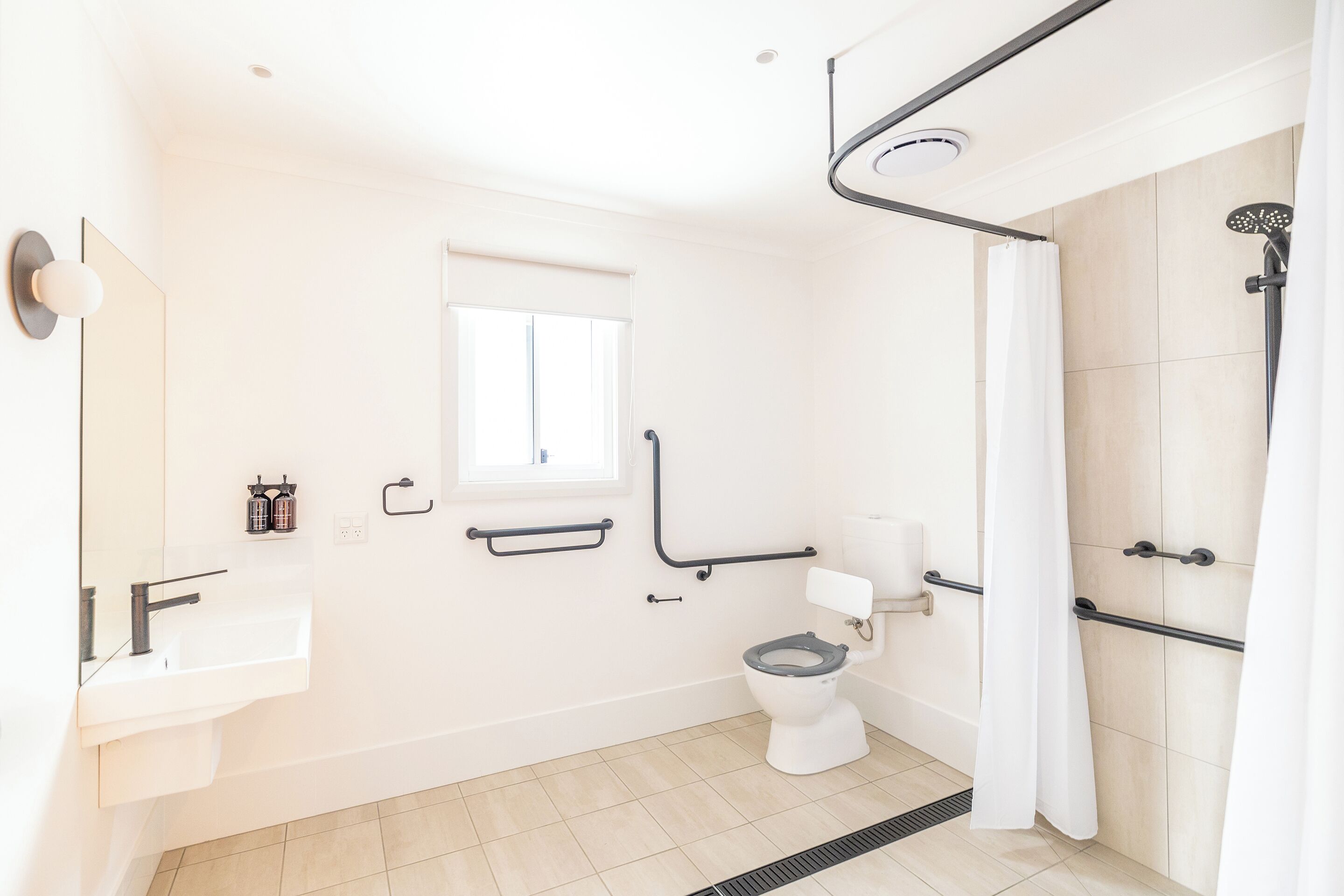 A modern bathroom with a white sink, toilet, and shower area.