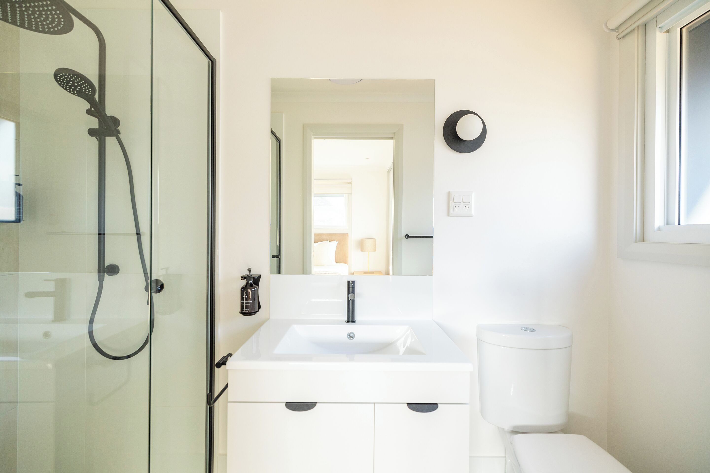 A modern bathroom with a glass shower enclosure, a white sink, and a toilet.