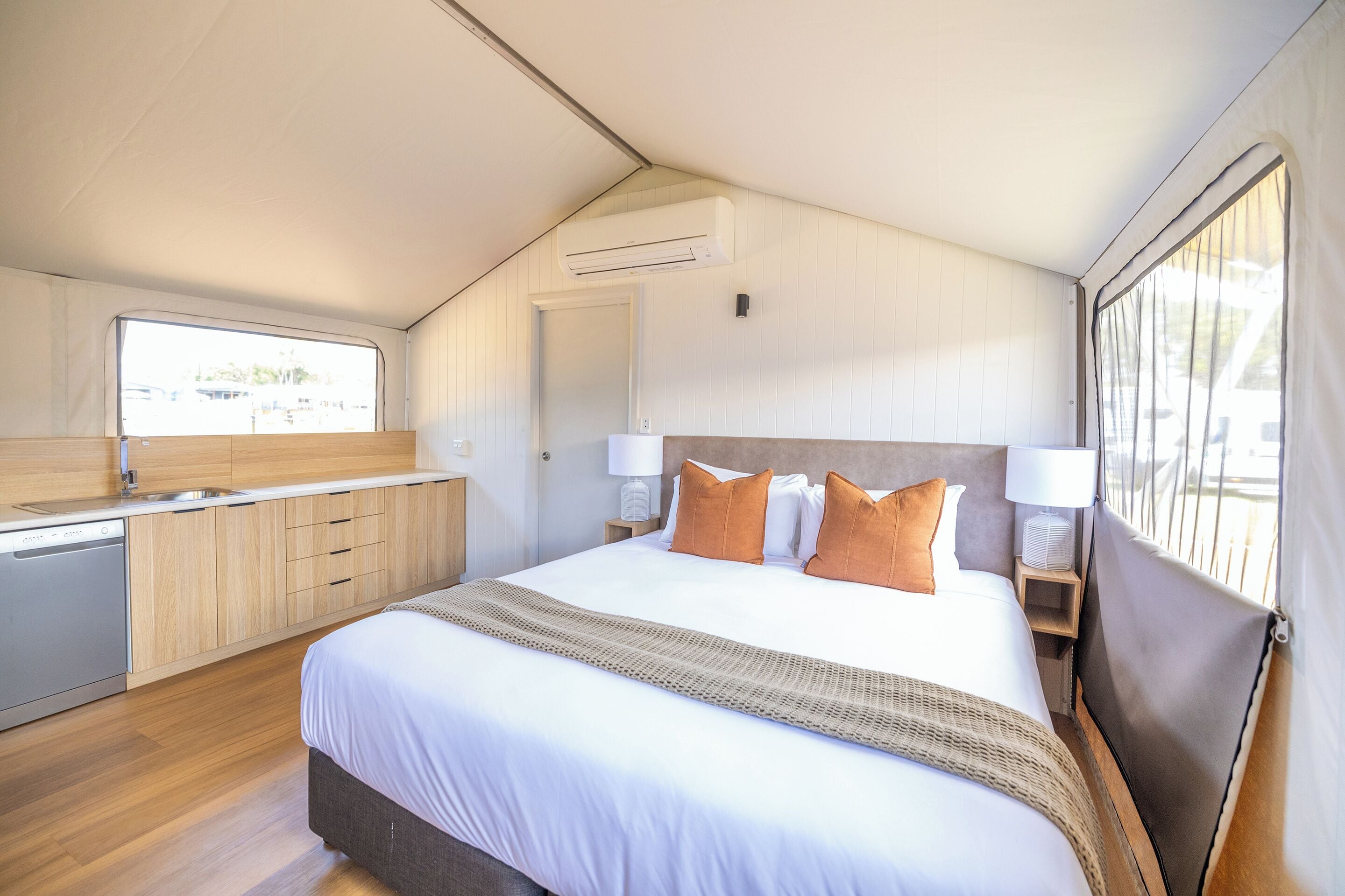 Une chambre moderne avec un grand lit, une commode en bois, un bureau intégré et une fenêtre donnant sur un beau paysage.