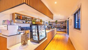L’intérieur d’un café moderne, avec un comptoir en bois, une vitrine et des étagères remplies de divers articles.