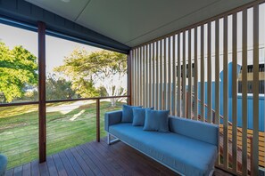 Un espace extérieur moderne, aménagé avec une terrasse en bois et un canapé bleu.