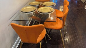 A dining area with a glass table set for four, surrounded by orange chairs. - Spacious 3 bedroom Townhome in the heart of Baltimore  (Baltimore)