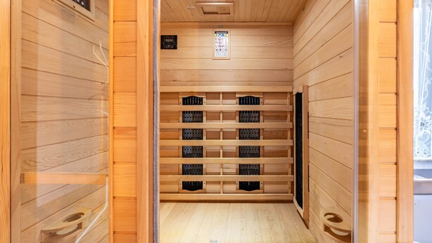 A wooden interior with a digital clock, a small window, and a shelf with black objects. - Holiday Home 'Eiffelperle' with Private Terrace, Garden, Infrared Sauna & Wi-Fi (Kaisersesch)