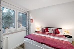 Ein Schlafzimmer mit Bett, Nachttischlampen, einem Fenster und einer Heizung.